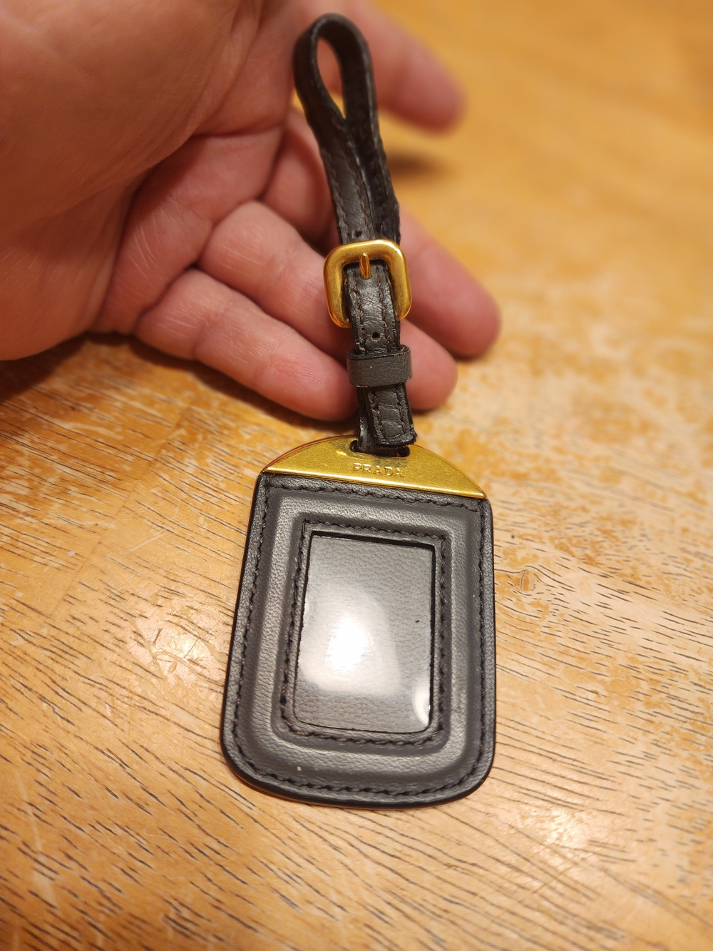 black leather Prada luggage tag or ID badge holder with gold-tone hardware.